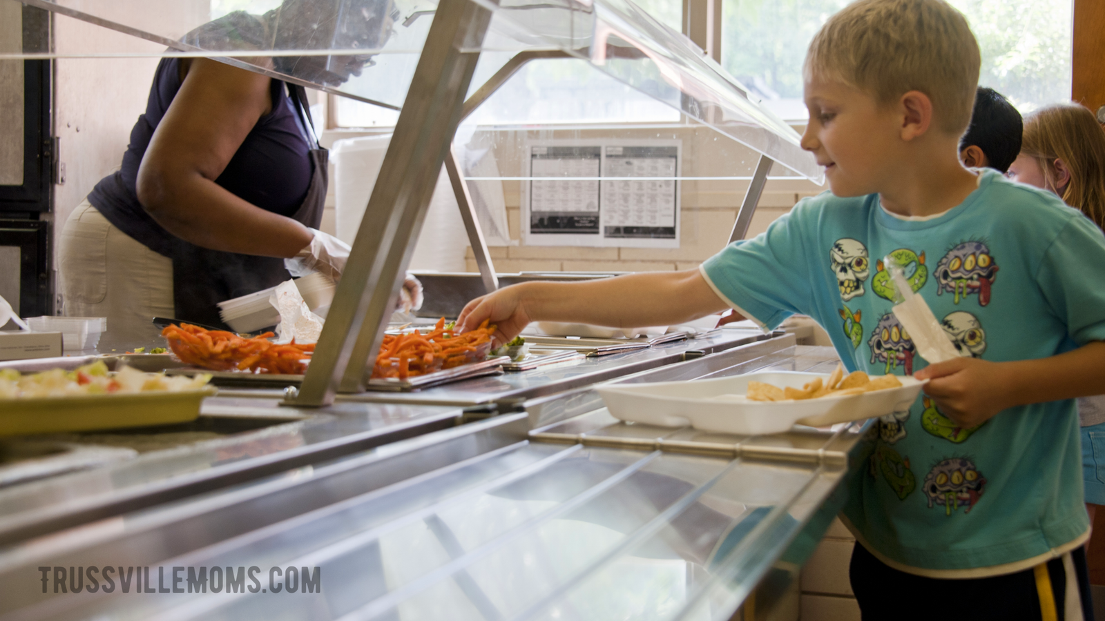 Young boy grabbing a food tray in the school cafeteria